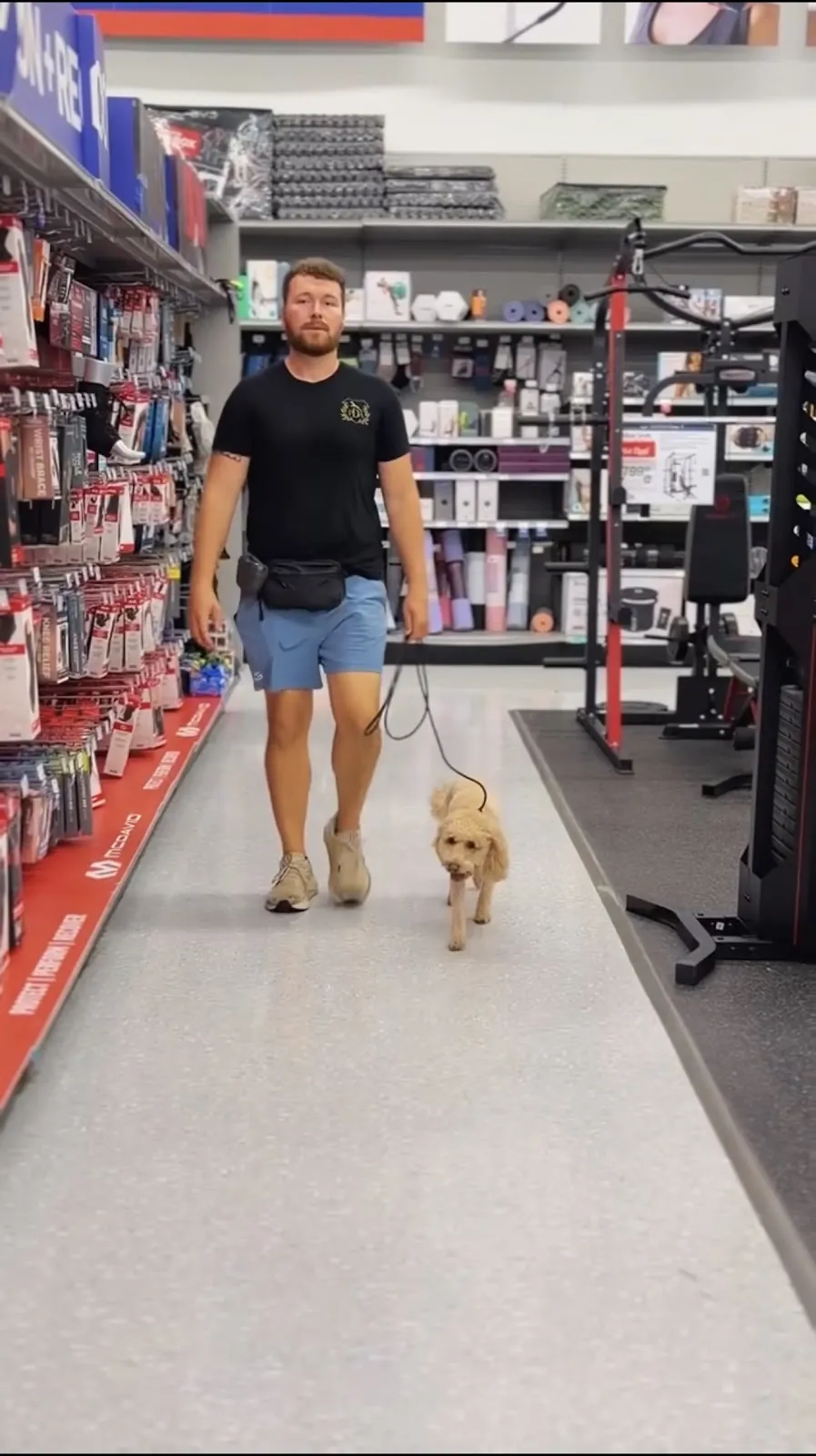 Our trainer walking a dog through a pet store aisle on a board and train field trip